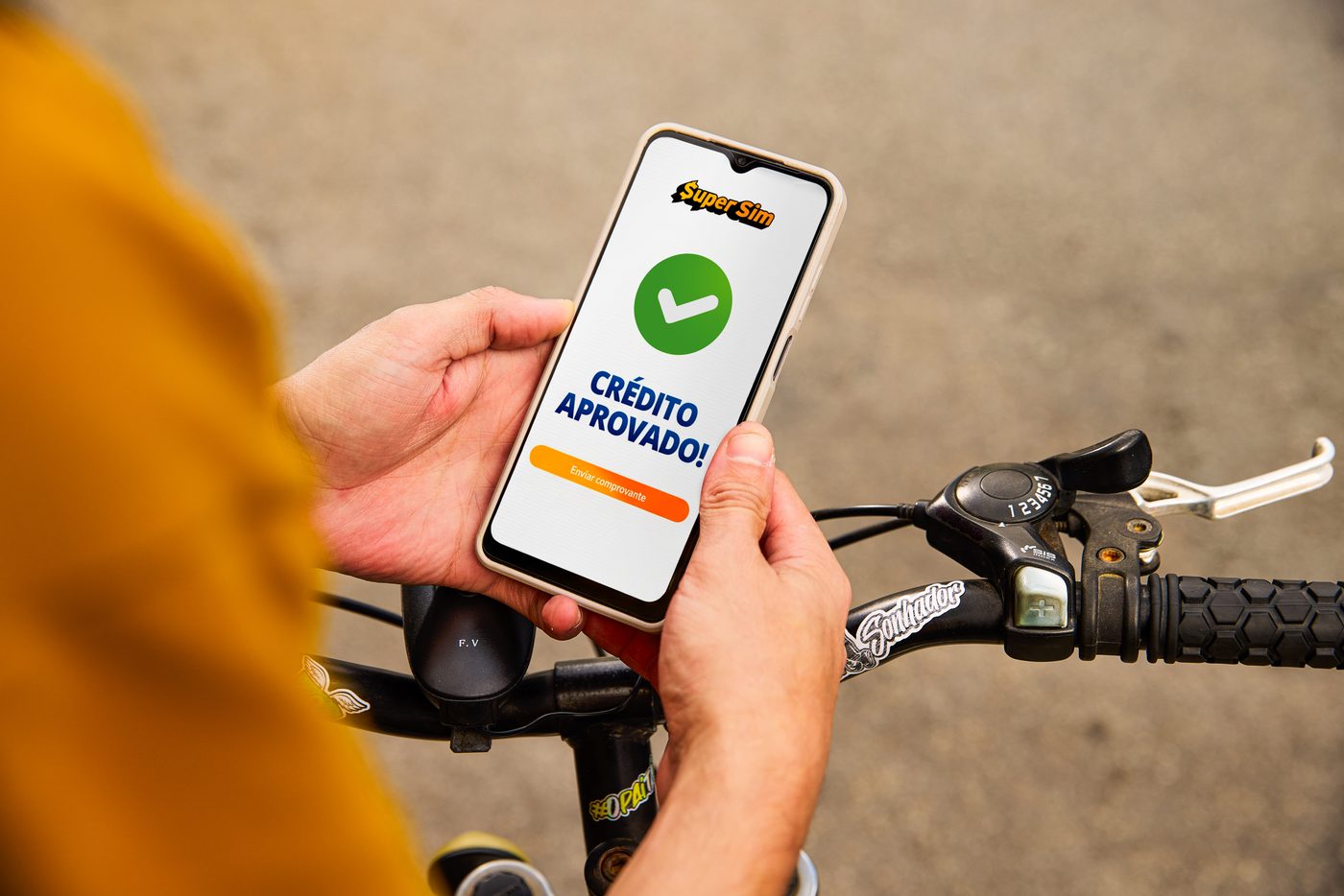 Tela de crédito aprovado no celular, preso ao guidão da bicicleta